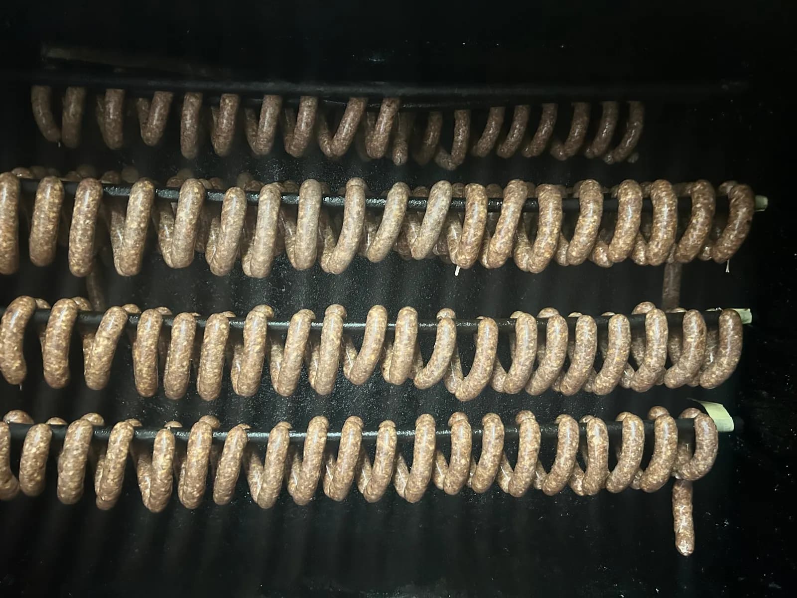 Frische Rauchwurst hängt auf Stangen in der Rauchkammer, noch hell